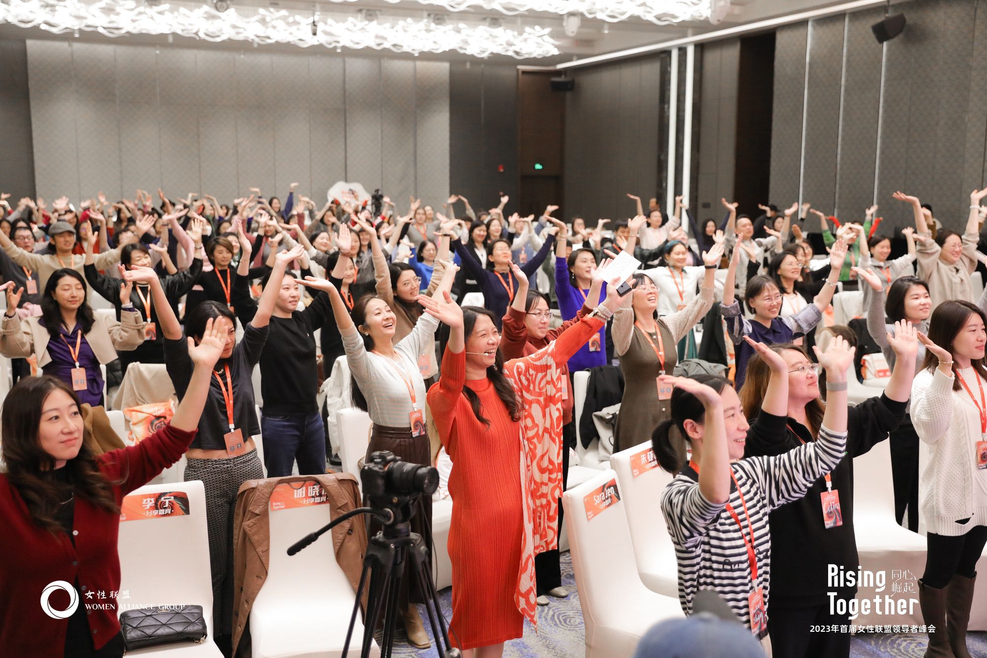 A full room of women at the Women Alliance Group Leadership Summit, arms raised and smiling