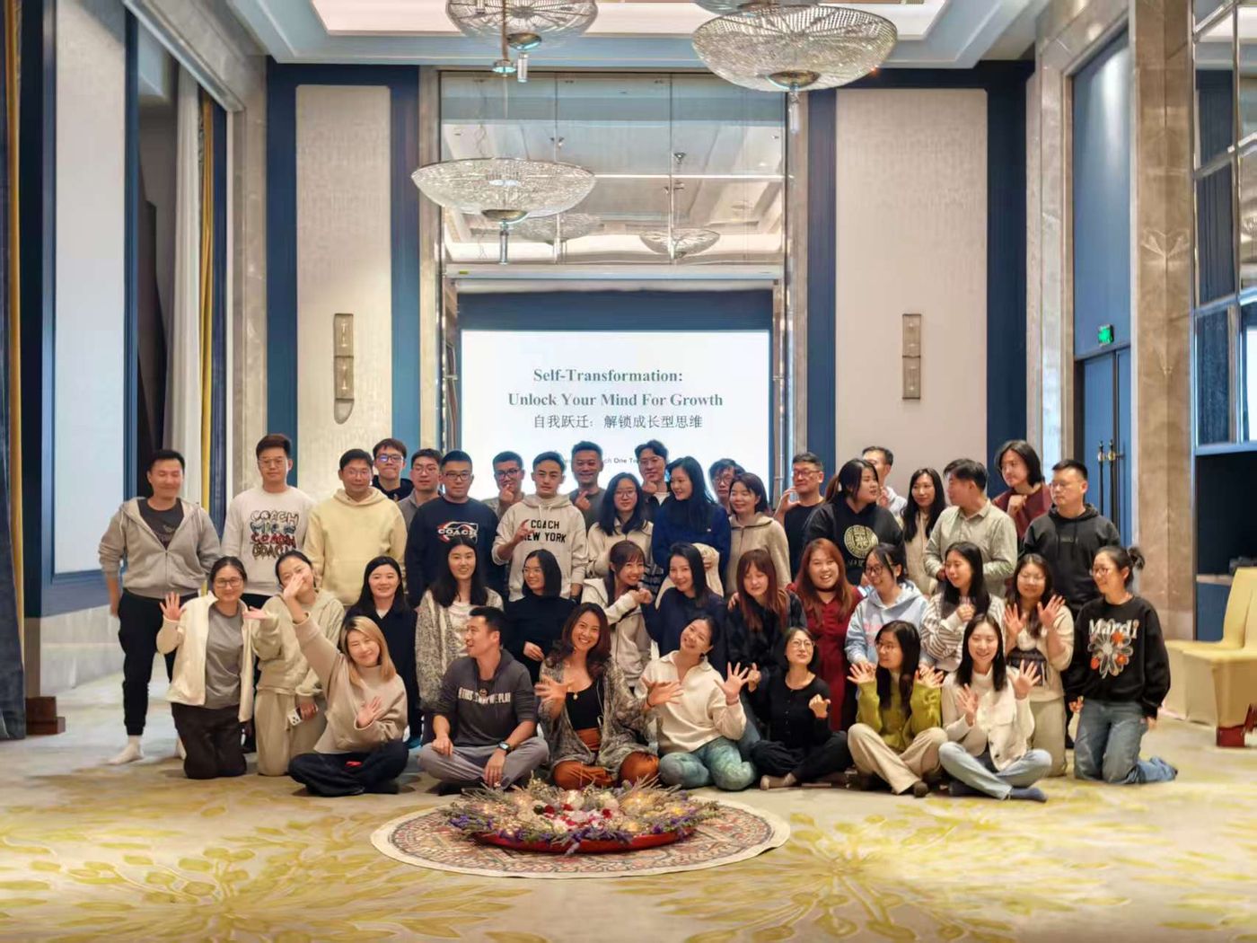 Workshop participants seated together around a circle of flowers after a self-transformation session